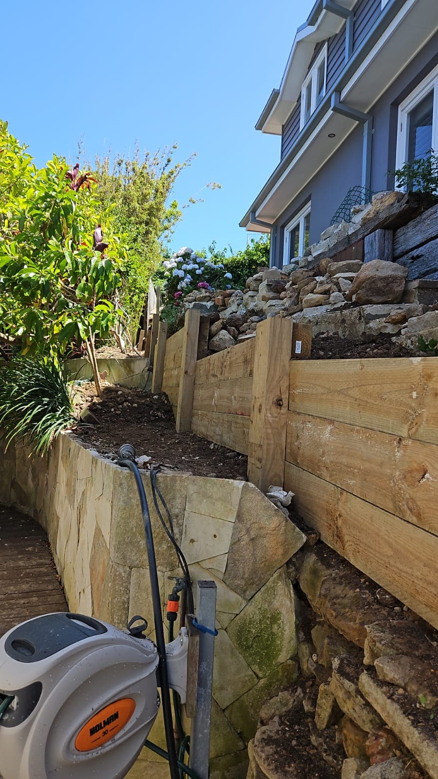 Timber retaining wall construction underway with drainage planning