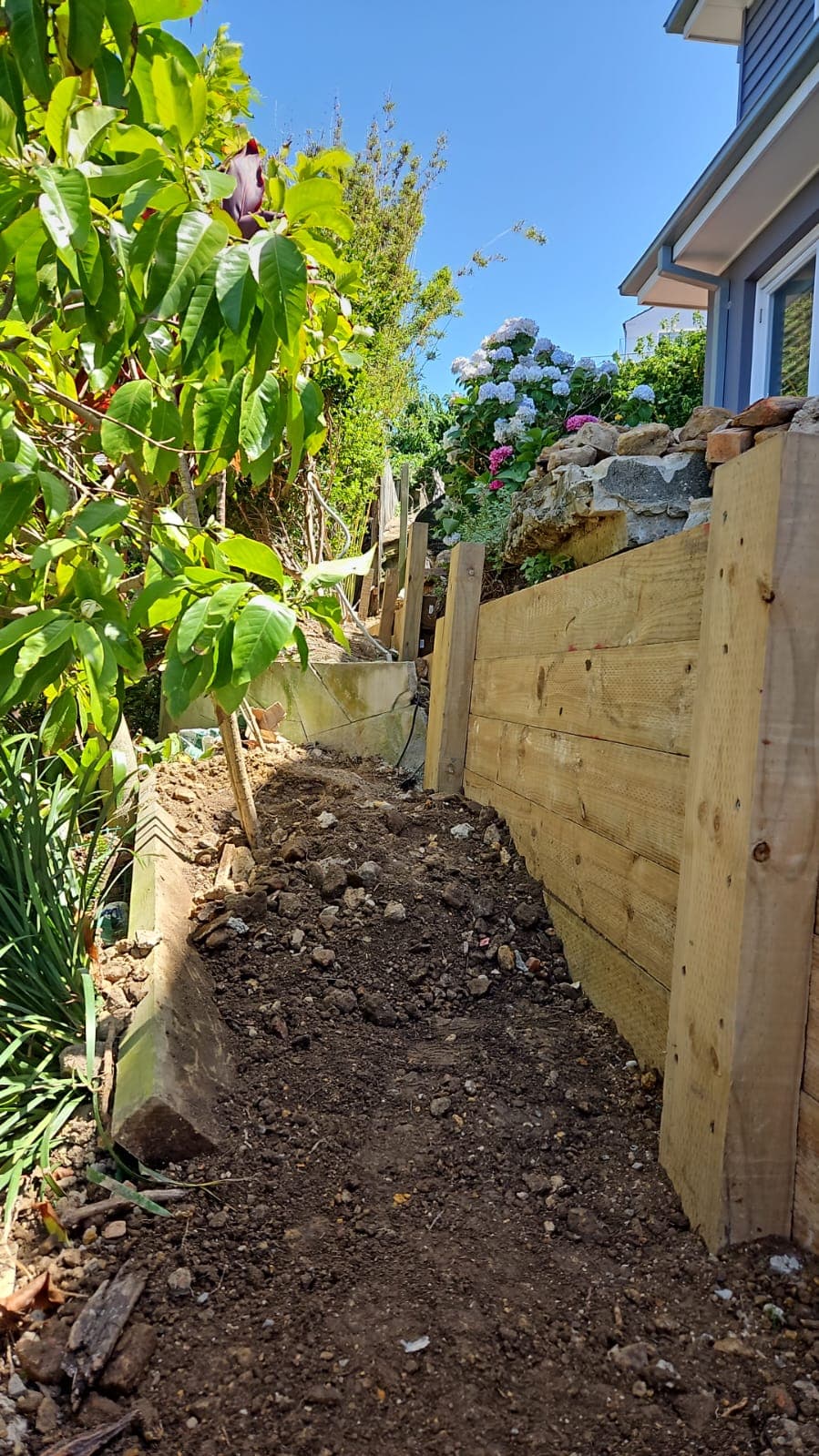 Drainage and backfill work behind the treated timber wall