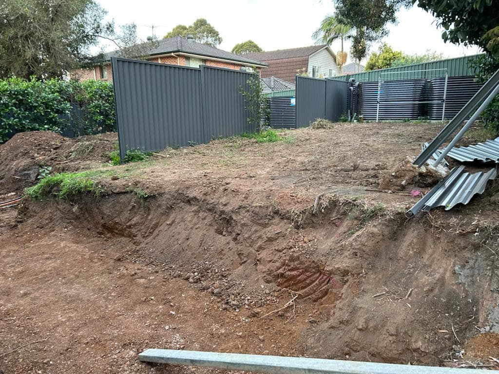 Uneven lawn and loose garden edges before the rebuild